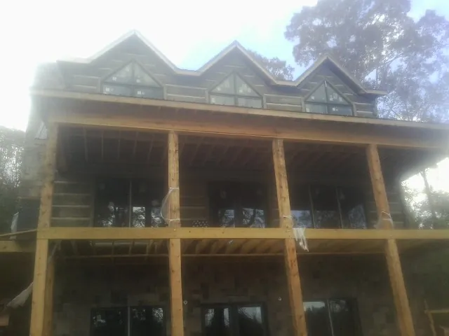 Dormers and porch framing on a large log home under construction — Roof Coating work by our crew in Poplarville